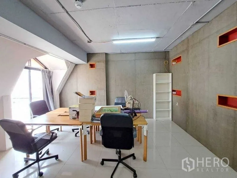Retail Space for rent in Khlong Toei, Bangkok - Workroom with concrete walls, desks, shelving and a large window.