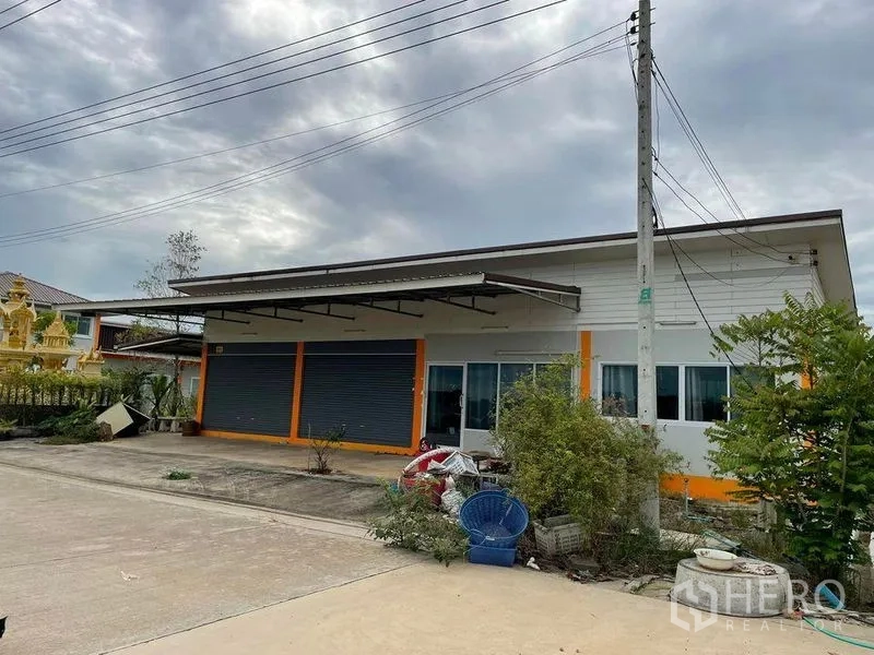 Warehouse for rent or sale in Pathum Thani - Single-story shopfront with twin roller shutters and a covered loading canopy.