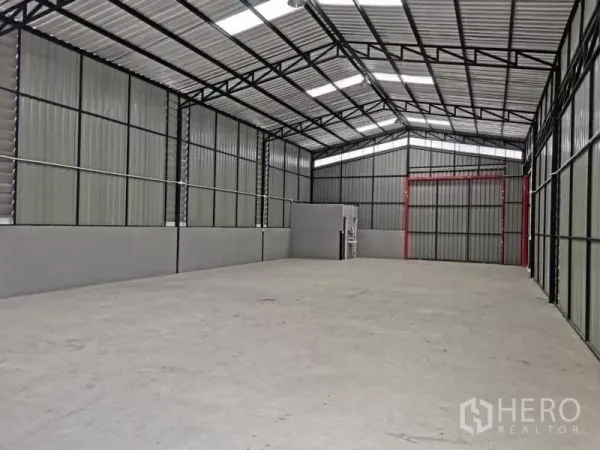 Warehouse for rent in Wang Thonglang, Bangkok - Spacious, high‑ceiling warehouse interior with steel trusses, roof skylights and a large concrete floor area.