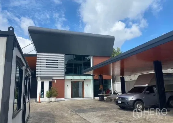 Home Office for rent or sale in Bang Khae, Bangkok - Contemporary two-storey home office in Bang Khae with wide driveway and covered parking under blue sky.