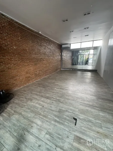 Retail Space for rent - Open-plan retail interior with brick feature wall, wood-look flooring and mirror at the rear.