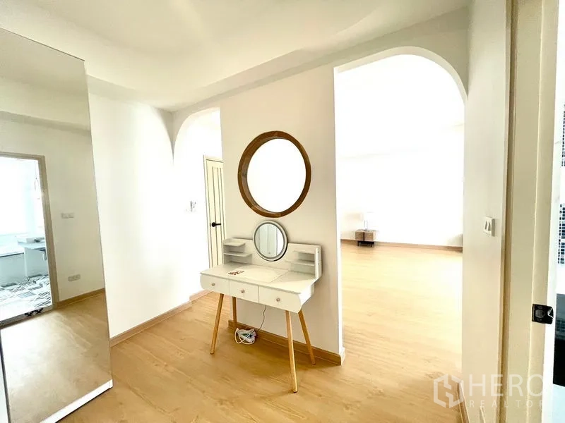 Townhouse for rent in Khlong Toei, Bangkok - Dressing nook with white vanity and round mirror beside an archway.