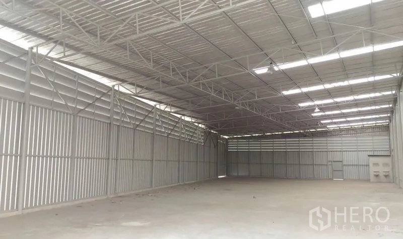 Warehouse for rent in Pathum Thani - Open-plan storage hall with ventilated metal walls and a wide-span roof.