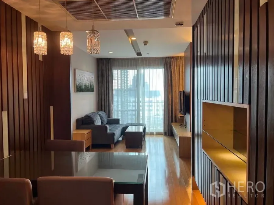 Condominium for rent in Khlong Toei, Bangkok - Living and dining room with crystal pendant lights, sofa set, TV console, and balcony doors.