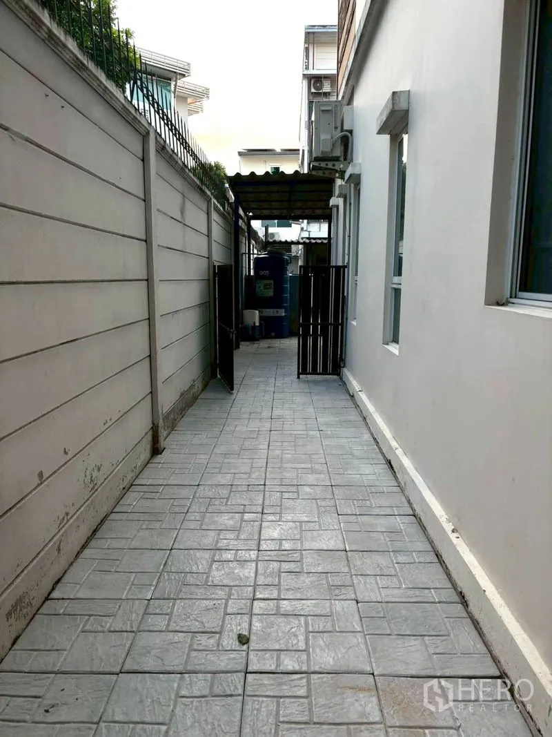 Townhouse for rent in Suan Luang, Bangkok - Paved side walkway along the townhouse with gate and utility area.