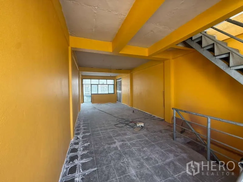 带办公室的家 出租在Khlong Toei, Bangkok - 黄色墙面的开放式楼层，灰色地砖与内部楼梯，便于办公布局。
