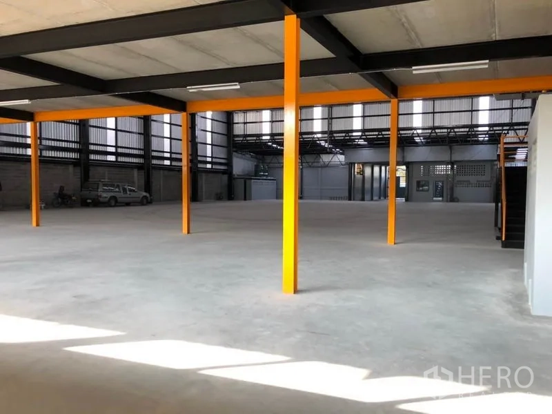 Warehouse for rent in Khlong Toei, Bangkok - Open-plan floor with bright orange support columns and mezzanine structure providing added workspace.