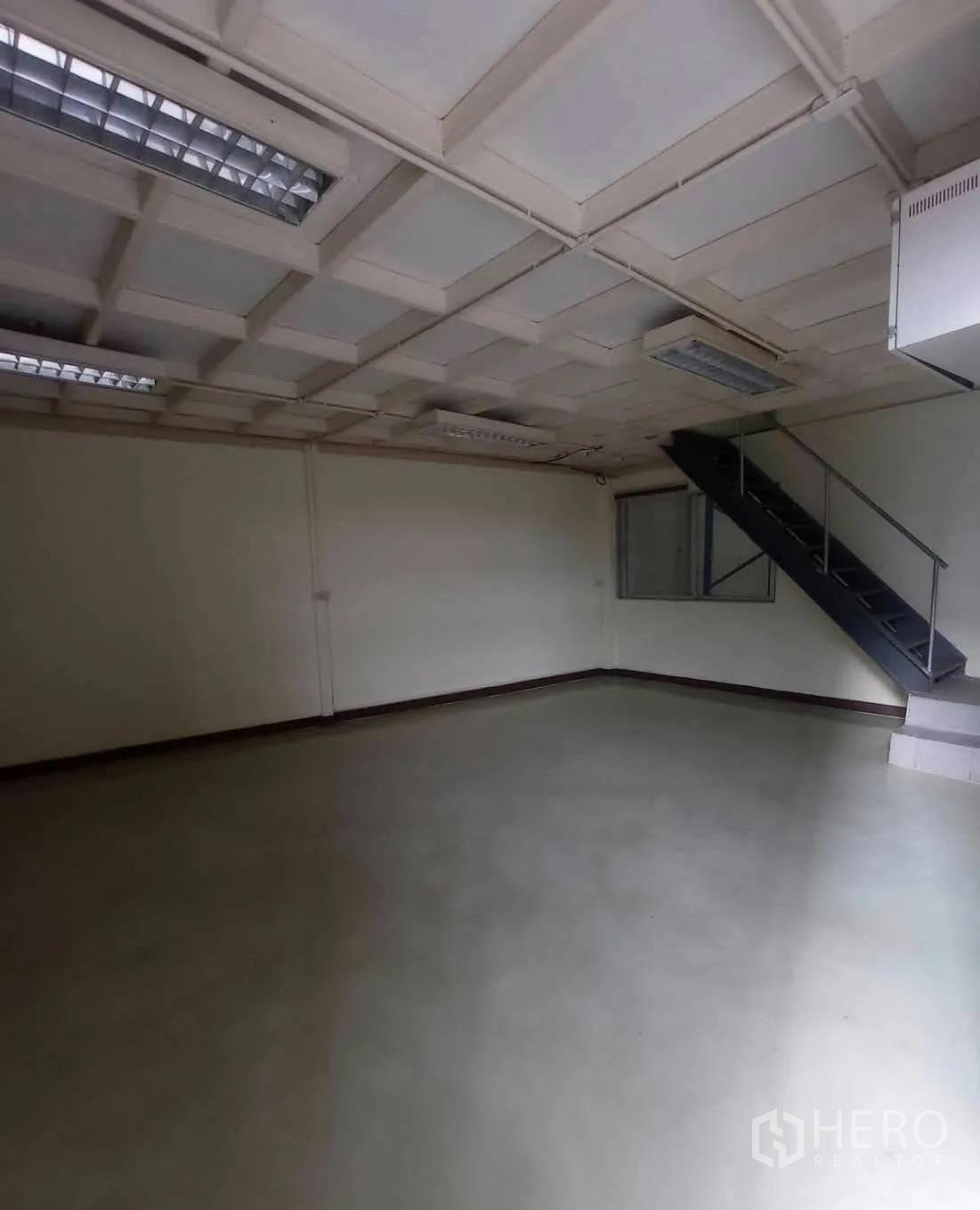 Warehouse for rent in Suan Luang, Bangkok - Empty office space with staircase to upper level and suspended lights.