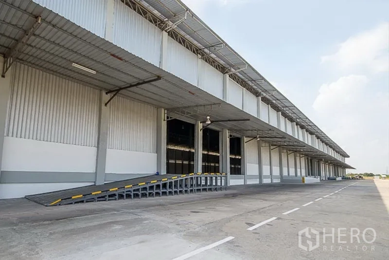 Warehouse for rent in Phra Nakhon Si Ayutthaya - Covered loading ramp and wide driveway for trucks beside the warehouse exterior.