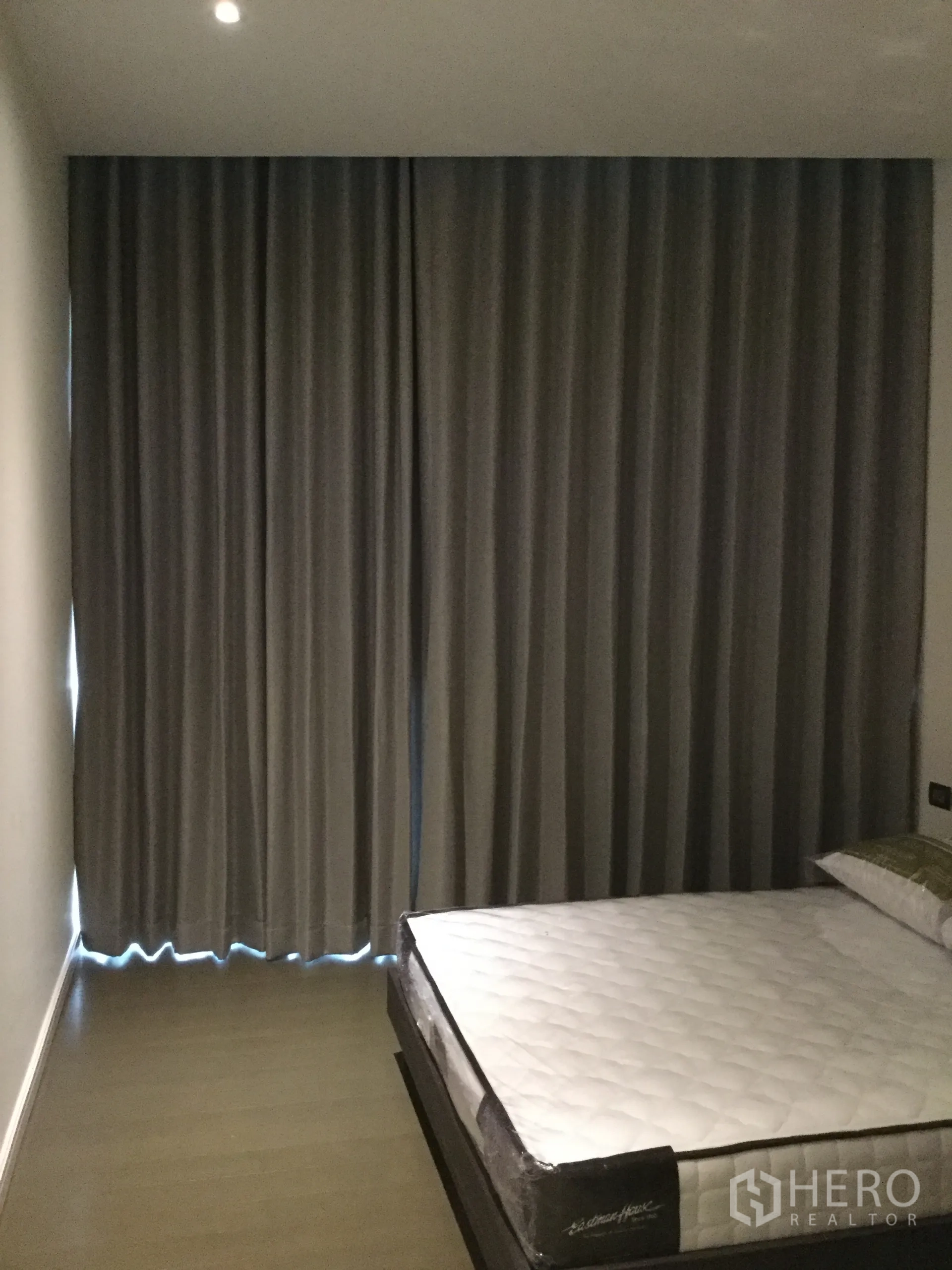 Condominium for rent in Pathum Wan, Bangkok - Bedroom with platform bed and blackout curtains, recessed lights and wood floors.