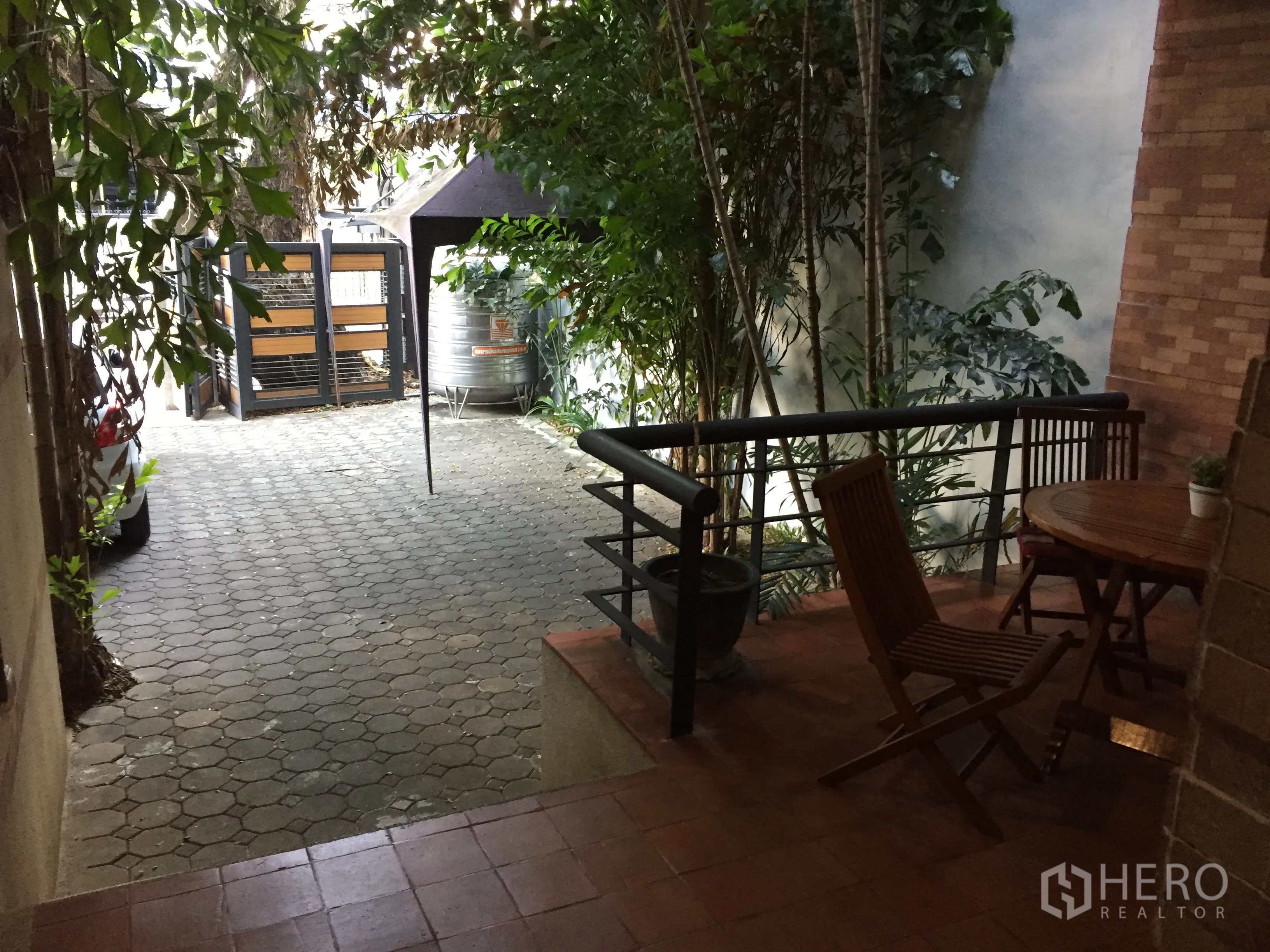 联排别墅 出租在Watthana, Bangkok - 带木质餐桌的前庭露台，铺砖车道与入户大门