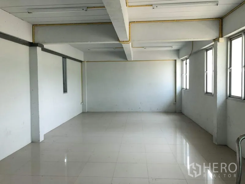 Factory for rent in Lam Luk Ka, Pathum Thani - Clean tiled office room with multiple windows and fluorescent lighting.