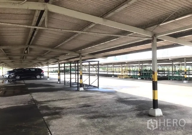 Factory for rent in Bang Bua Thong, Nonthaburi - Under large metal carport showing covered parking and storage racks.