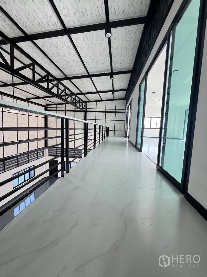 Warehouse for sale in Lam Luk Ka, Pathum Thani - Mezzanine walkway beside glass-partitioned offices and insulated steel truss ceiling.