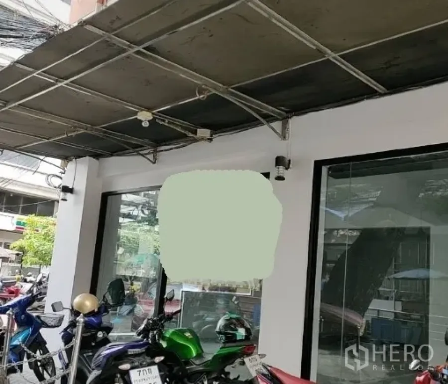 Retail Space for rent in Bang Rak, Bangkok - Street-level retail shopfront with large glass windows, a metal awning, and parked motorcycles in urban Bang Rak, Bangkok.