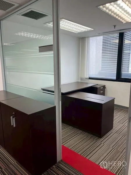 Office Space for rent - Furnished manager’s office with desk, storage cabinets, and window.