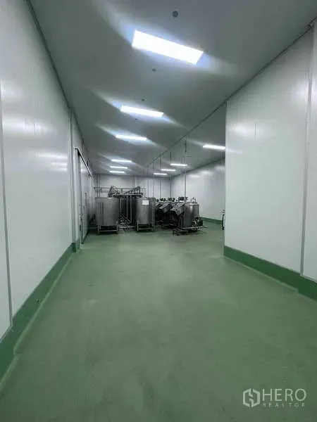 Factory for rent - GMP-grade cleanroom corridor with green epoxy flooring and stainless tanks under bright LED lighting.