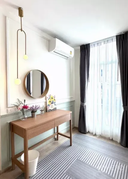 Townhouse for rent in Prawet, Bangkok - Sunny work corner with console desk, round mirror, full-height curtains and air conditioner.