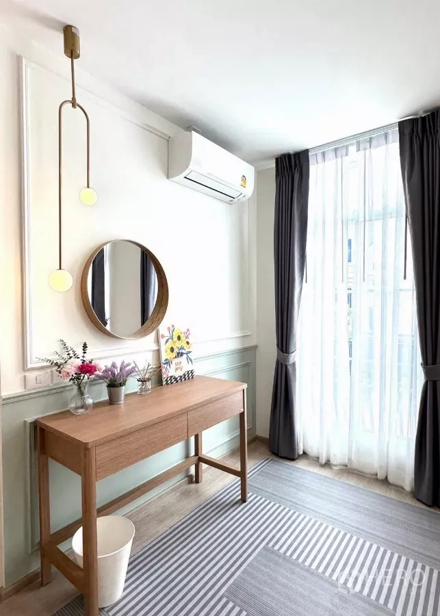 Townhouse for rent in Prawet, Bangkok - Sunny work corner with console desk, round mirror, full-height curtains and air conditioner.