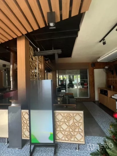 Retail Space for rent in Watthana, Bangkok - Entrance interior with wood accents, decorative screens, and seating facing a glass doorway.