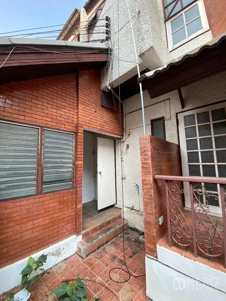 Home Office for rent in Pathum Wan, Bangkok - Rear service area with red brick wall, metal awning and small steps.