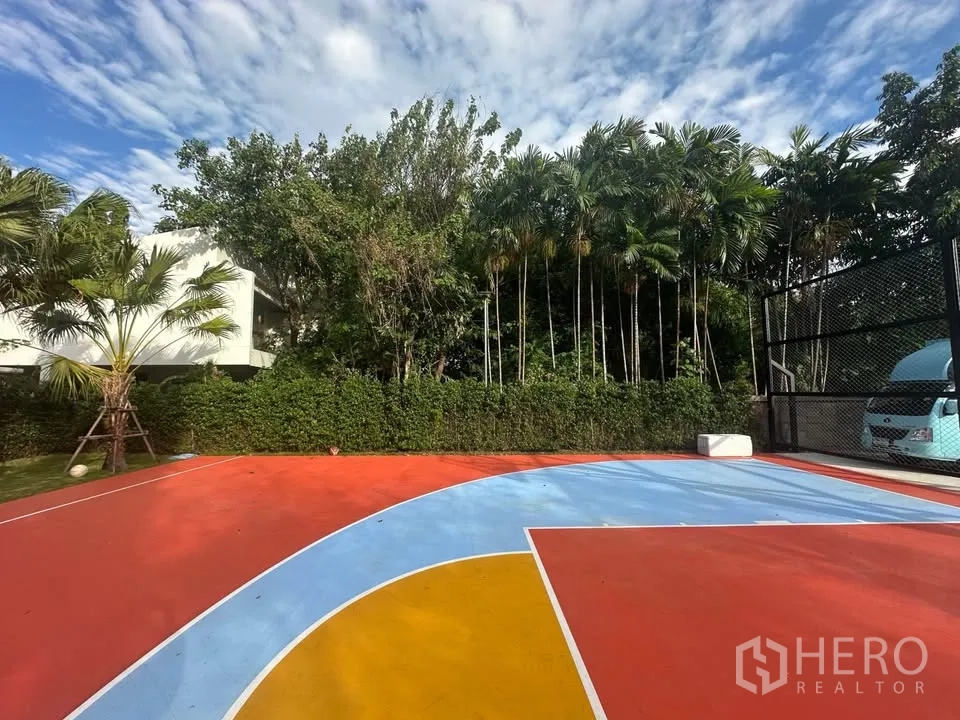 Land for rent in Watthana, Bangkok - Vibrant court surface bordered by tall trees and hedges offering privacy on a Sukhumvit land plot.