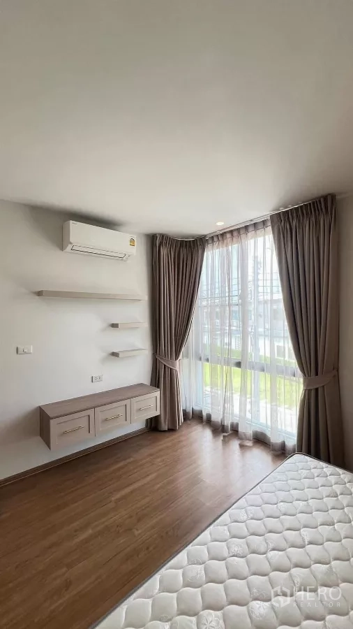 Townhouse for rent in Bang Phli, Samut Prakan - Bedroom corner with floor-to-ceiling window, sheer curtains and floating shelves.