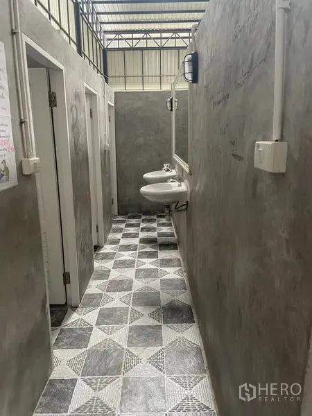 Warehouse for rent in Saphan Sung, Bangkok - Restroom area featuring wall-mounted sinks, stalls and geometric tile flooring in the warehouse.