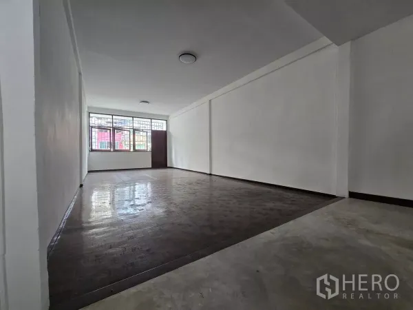 Shophouse for rent in Watthana, Bangkok - Wide ground‑floor shop space with white walls, front windows and timber floor.