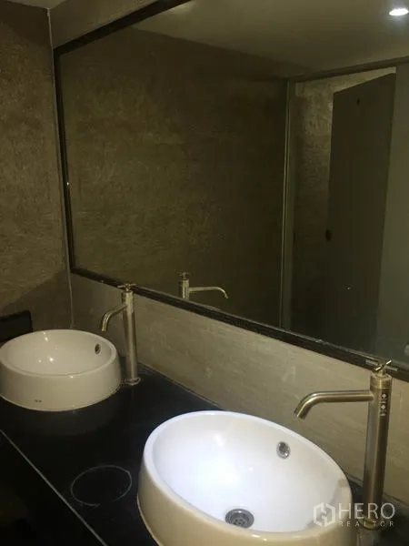 Office Space for rent in Watthana, Bangkok - Modern restroom with two round basins, large mirror and stone-textured walls.