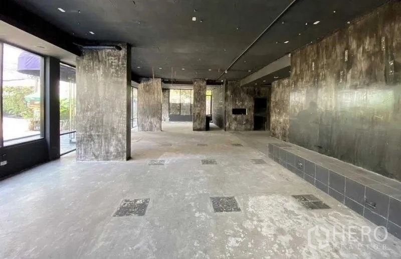 Retail Space for rent in Khlong Toei, Bangkok - Open-plan retail hall with concrete columns and black ceiling, window frontage.