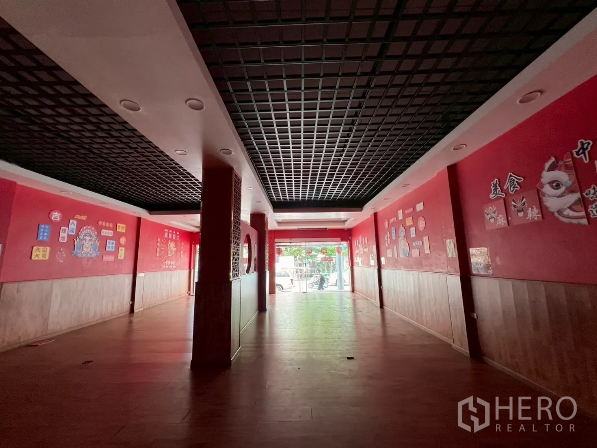 Shophouse for rent in Watthana, Bangkok - Long retail hall leading to a glass entrance with black lattice ceiling and wall graphics.