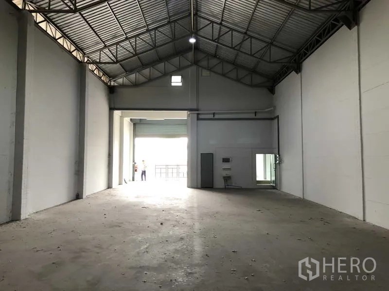 联排别墅 出售在Bang Bua Thong, Nonthaburi - 宽敞仓库大厅，钢桁架屋顶与大卷帘入口。