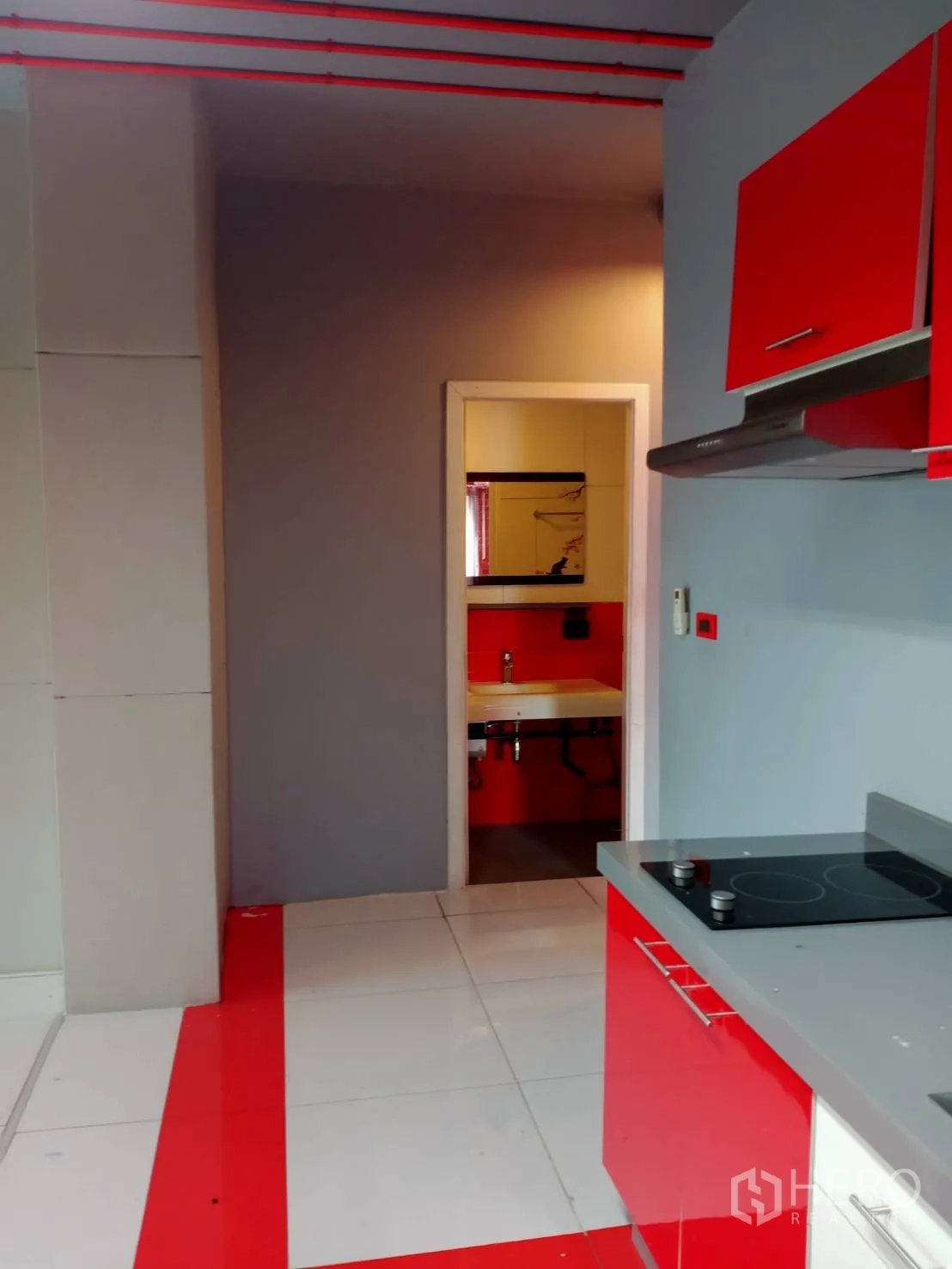 Office Space for rent in Khlong Toei, Bangkok - Compact pantry with red cabinetry, electric cooktop and a doorway to a private restroom.