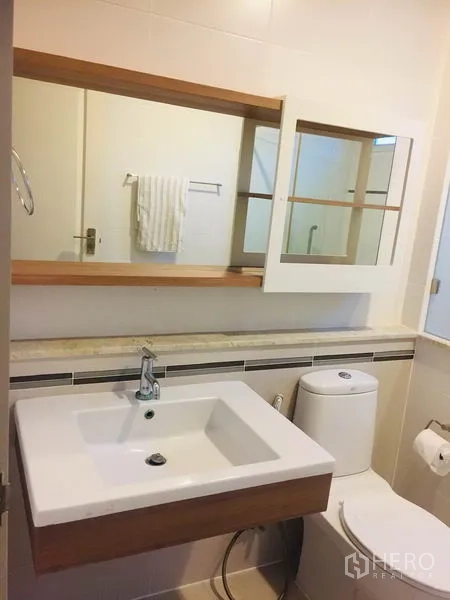 Detached House for rent in Bang Kapi, Bangkok - Bathroom vanity with square basin, mirror cabinet and toilet in a tiled space.