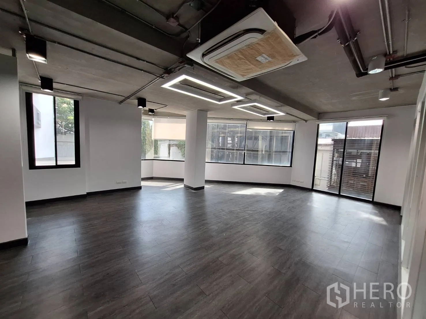 Office Space for rent - Bright workspace with square LED lights, industrial ceiling and floor-to-ceiling windows.