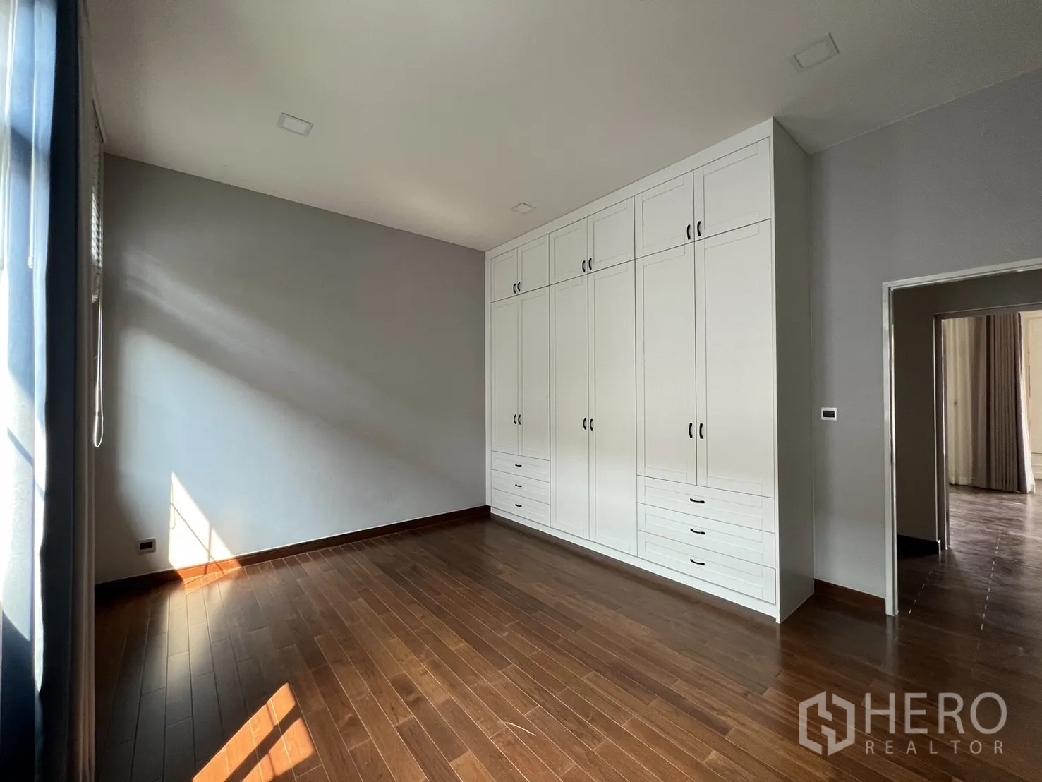 Detached House for rent or sale in Prawet, Bangkok - Bedroom with full wall built-in wardrobes and hardwood floors.