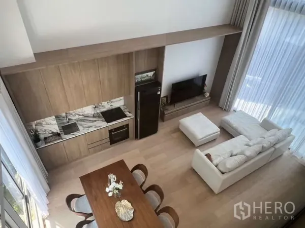 Townhouse for rent in Phra Khanong, Bangkok - View of double-height living area with open kitchenette, dining table and sofa set.