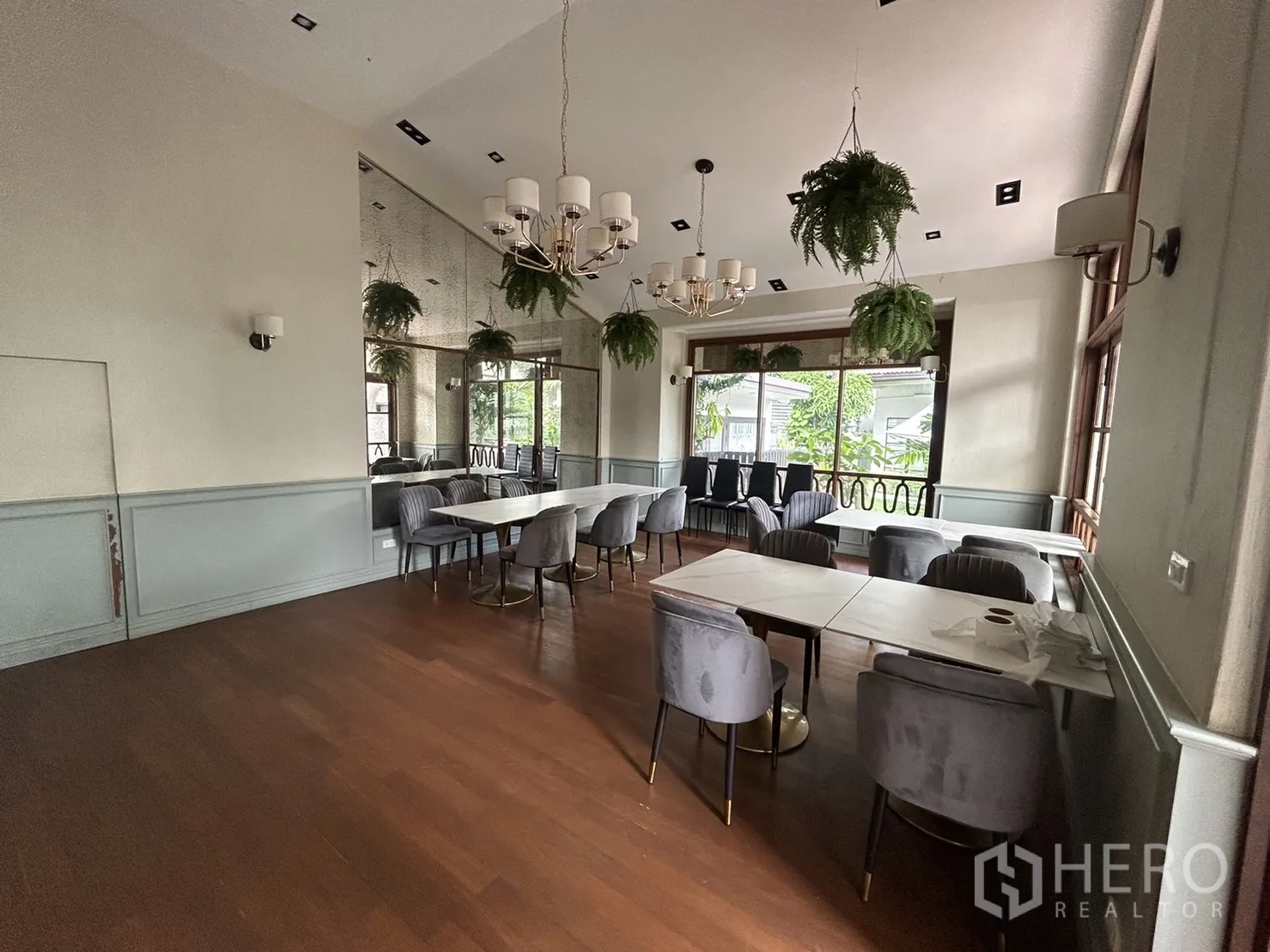 Retail Space for rent in Bangkok - Spacious seating area with mirrors, chandeliers, wood floors and greenery views through wide windows.
