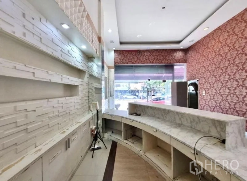Shophouse for rent in Watthana, Bangkok - Reception counter area with built‑in display shelves and ceiling lighting.