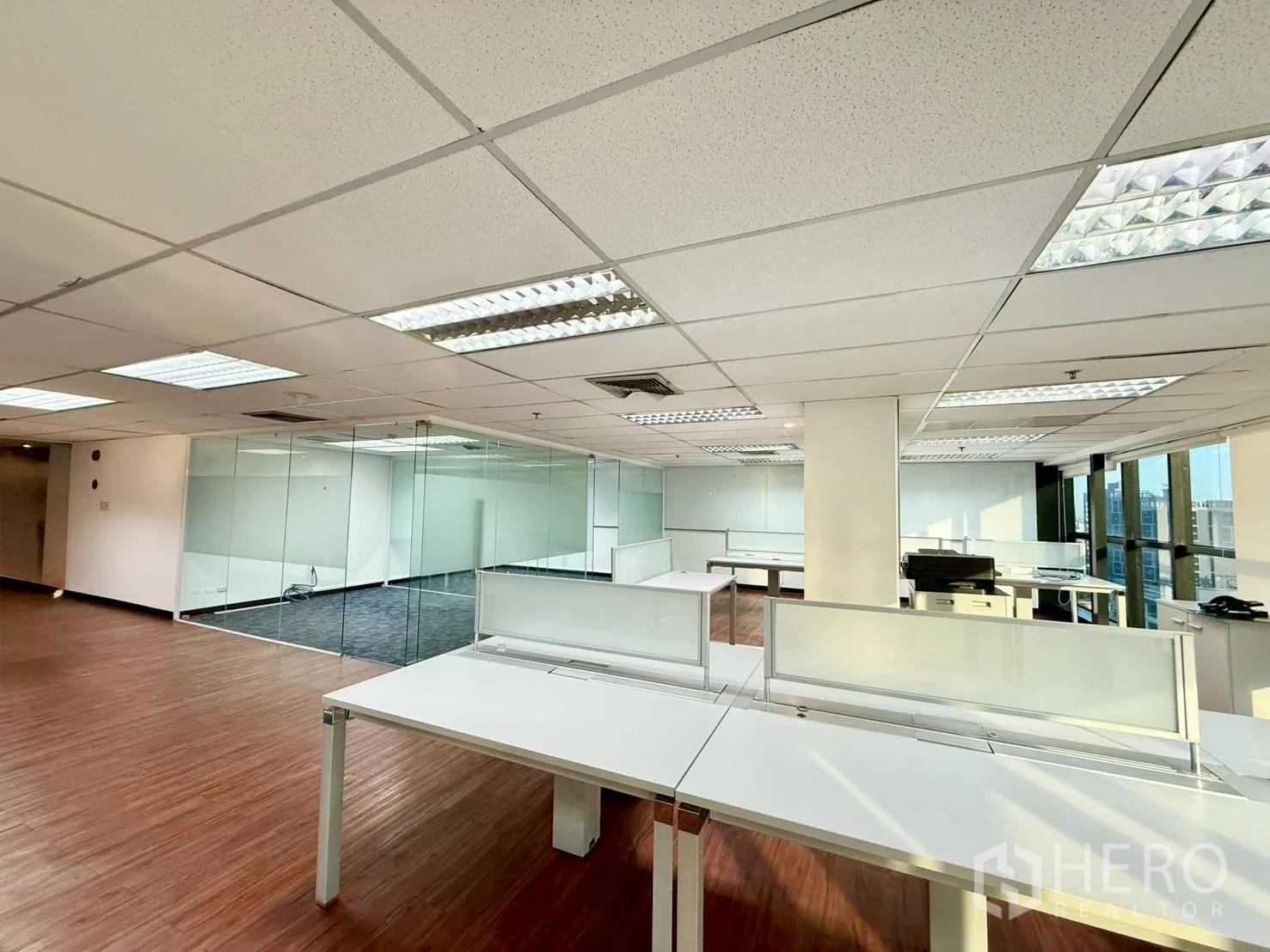 Office Space for rent in Watthana, Bangkok - Open workspace with bench desks, large windows, suspended ceiling, and a printer area.