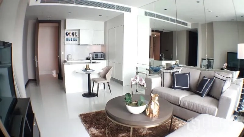 Condominium for rent in Khlong Toei, Bangkok - Modern living room with mirrored wall, open kitchen, dining set and sofa in a Bangkok condo near BTS Nana.
