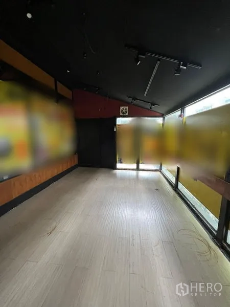 Retail Space for rent in Watthana, Bangkok - Narrow glass-fronted room with light wood floors and black ceiling track lights.