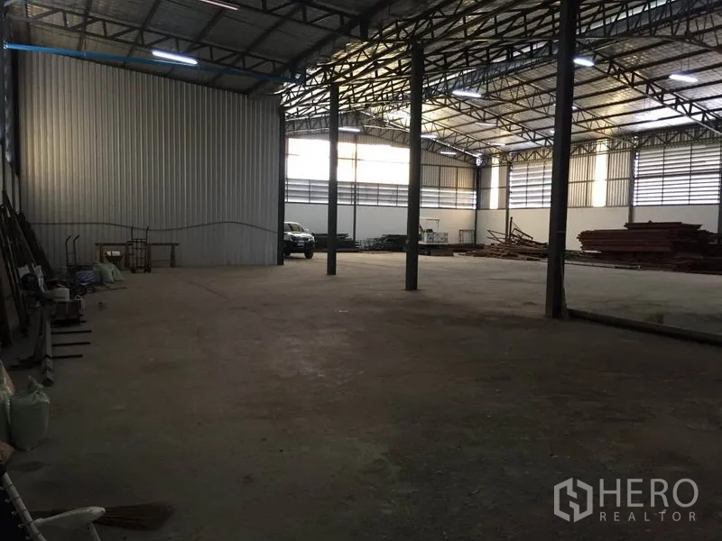 Warehouse for rent in Saphan Sung, Bangkok - Open storage space with steel columns, roller door access, and ample maneuvering area for vehicles.