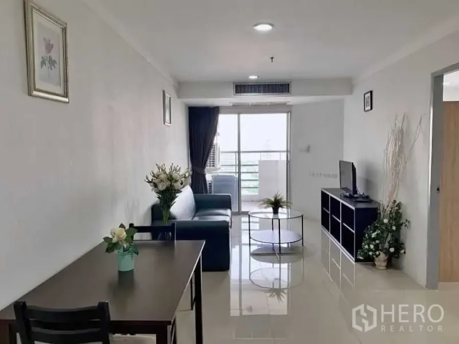 Condominium for rent in Khlong Toei, Bangkok - Bright living room with sofa, TV unit, dining table and balcony access in a Sukhumvit condo.