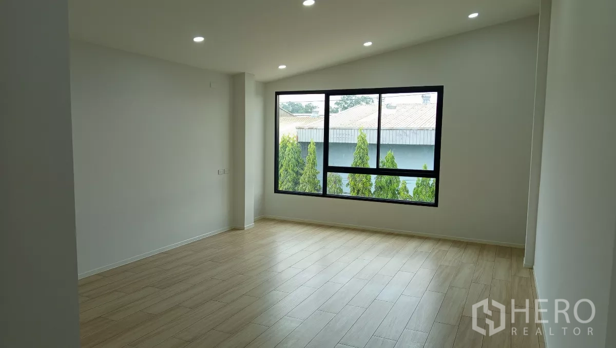 Warehouse for rent or sale in Lam Luk Ka, Pathum Thani - Upstairs office room with wood-look flooring and a wide window overlooking greenery.