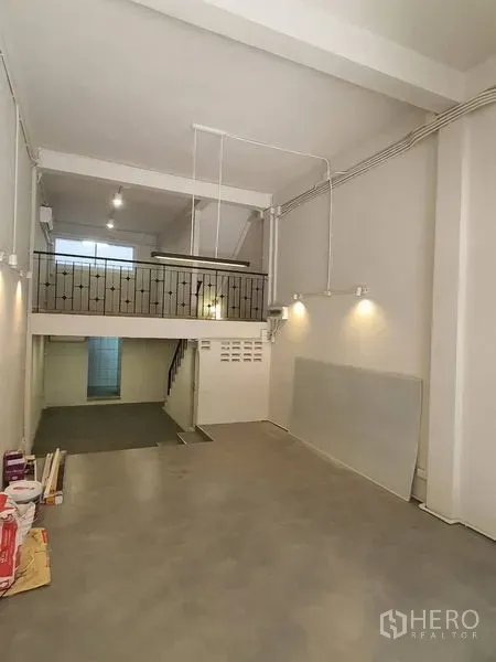 Shophouse for rent in Phra Khanong, Bangkok - Open-plan ground floor with high ceiling, mezzanine, concrete floor and feature lighting.