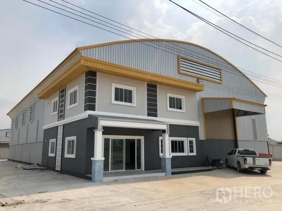 Factory for rent or sale in Bang Len, Nakhon Pathom - Front exterior of a modern factory with two-storey office, gold trim and a large roller shutter door.