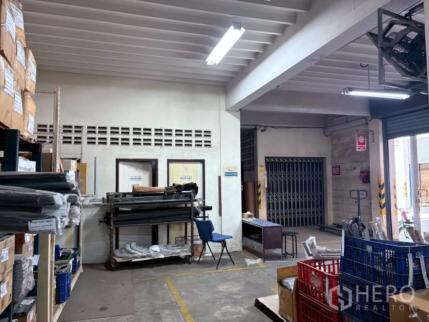 Factory for rent or sale in Bang Khun Thian, Bangkok - Packing and inventory room with shelves, boxes and a roller door.