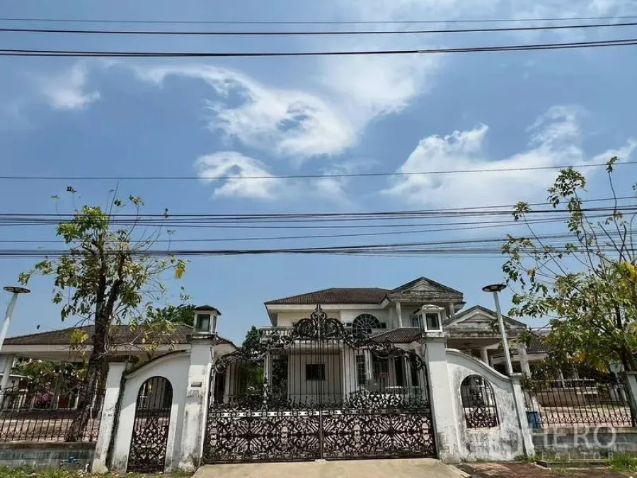 Detached House for rent in Prawet, Bangkok - Street view of a gated detached house with ornate wrought‑iron gate and white wall.